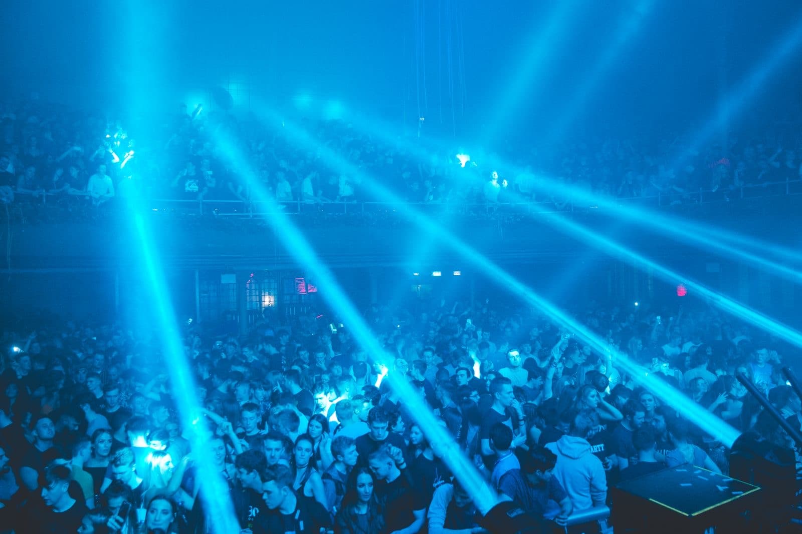 Crowd with hands up under blue lasers at a club night