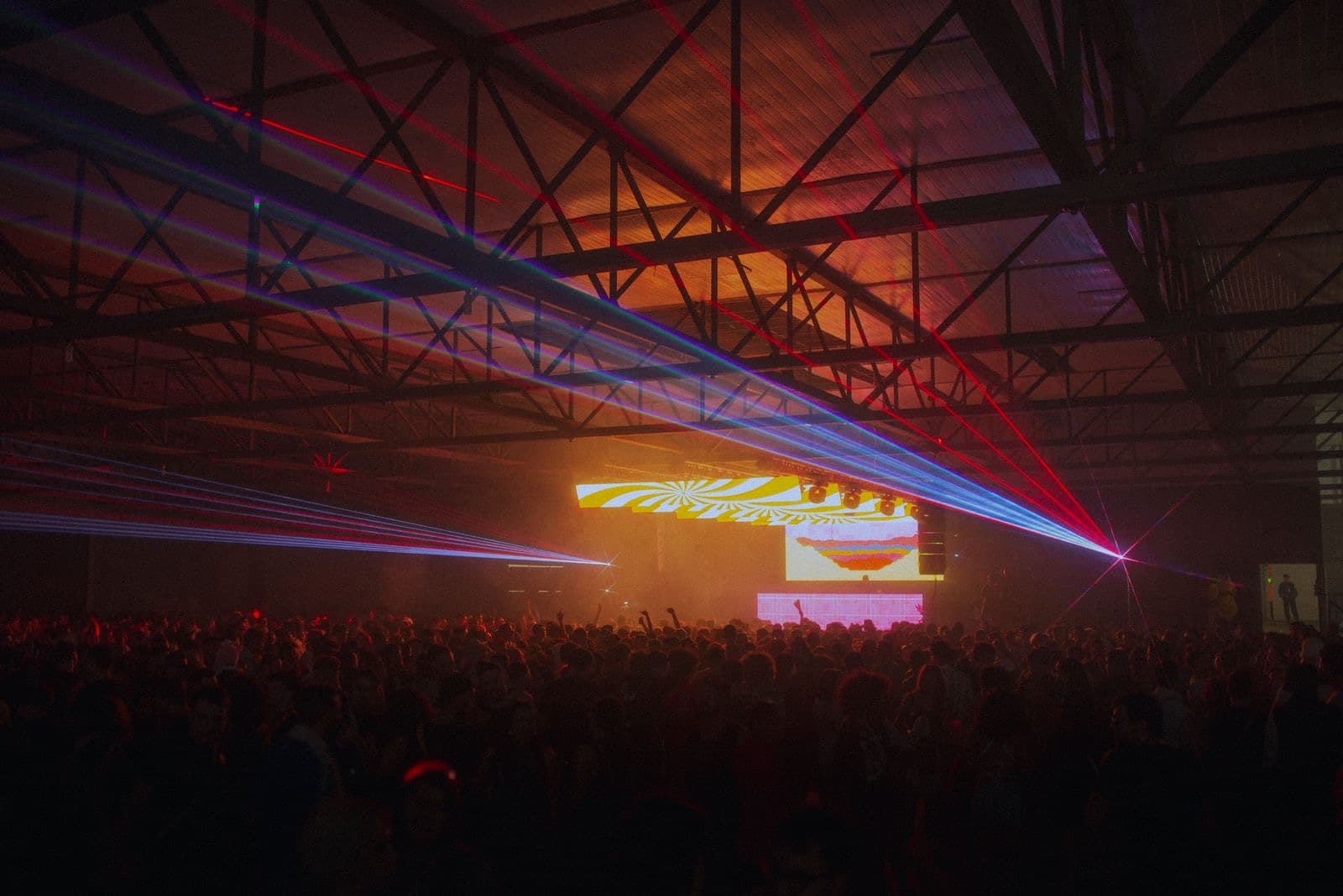 Indoor crowd beneath a grid of colored laser beams